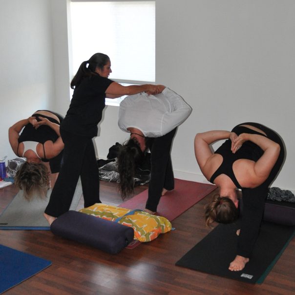 Female yoga teacher helping young people with yoga practice | Santosh Yoga Institute in Salt Lake City, UT