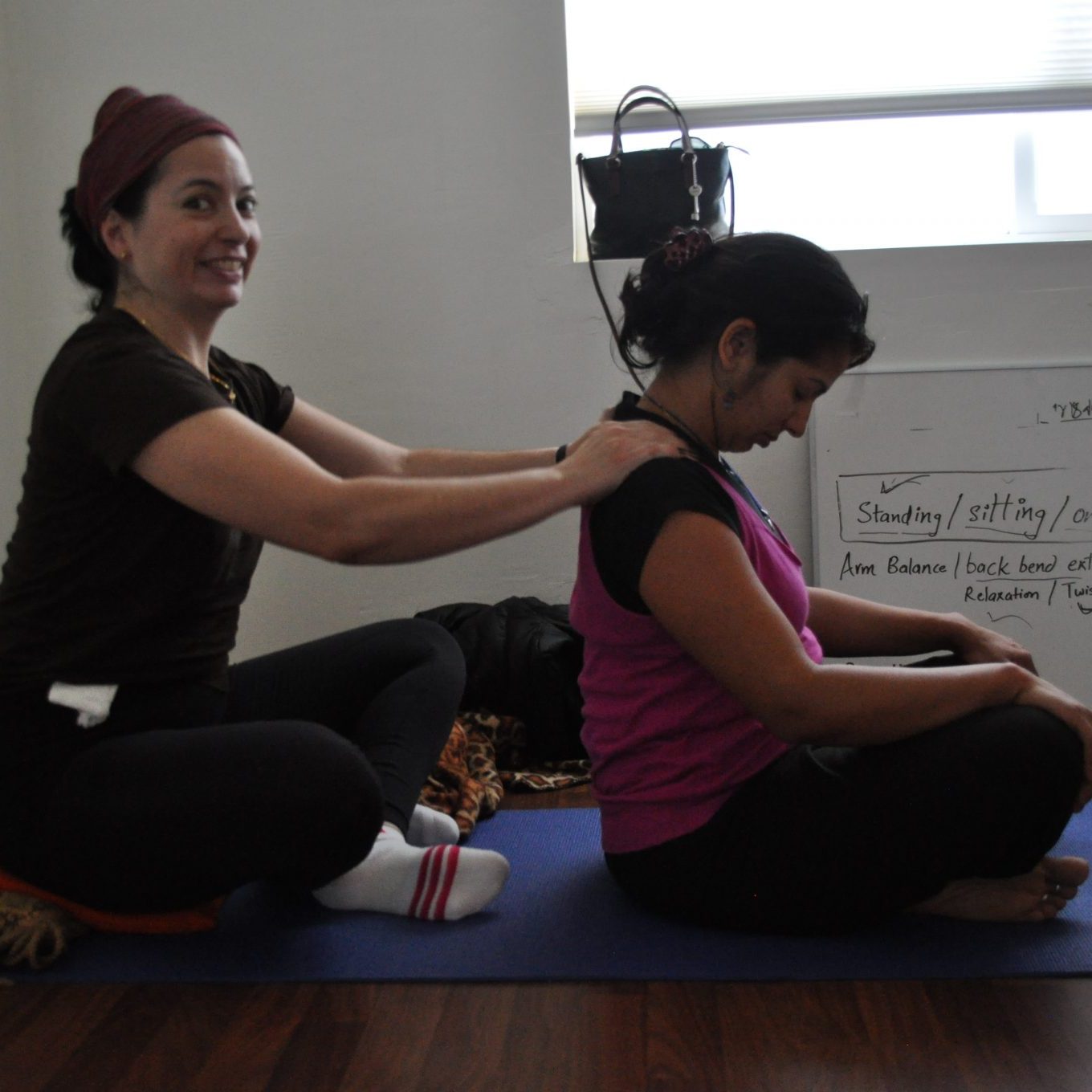 Young girl giving shoulder massage to young woman | Santosh Yoga Institute in Salt Lake City, UT