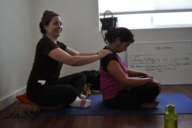 Young girl giving shoulder massage to young woman | Santosh Yoga Institute in Salt Lake City, UT