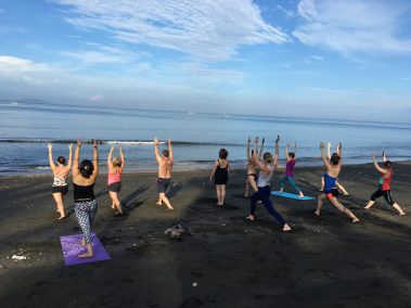 Group of people practicing yoga in front of beach | Santosh Yoga Institute in Salt Lake City, UT