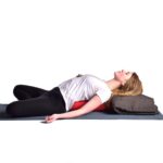 Woman doing yoga with junior bolster in Salt Lake City, UT | Santosh Yoga Institute