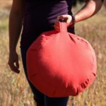 Man Holding Zafu Meditation Red Round Cushion in Salt Lake City, UT | Santosh Yoga Institute