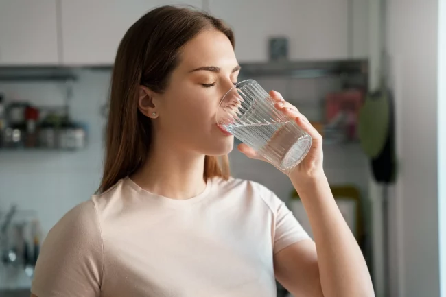 Young woman drinking water in Salt Lake City, UT | Santosh Yoga Institute