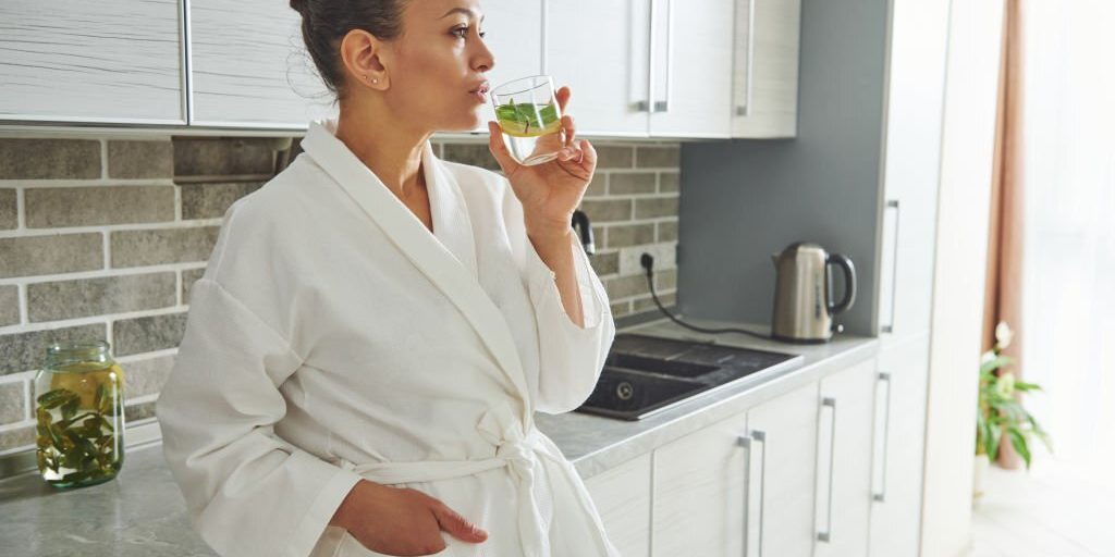 Young female drinking Water in the kitchen in Salt Lake City, UT | Santosh Yoga Institute