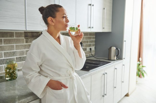 Young female drinking Water in the kitchen in Salt Lake City, UT | Santosh Yoga Institute