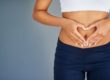 Fit young woman making a heart-shaped gesture over her stomach in Salt Lake City, UT | Santosh Yoga Institute