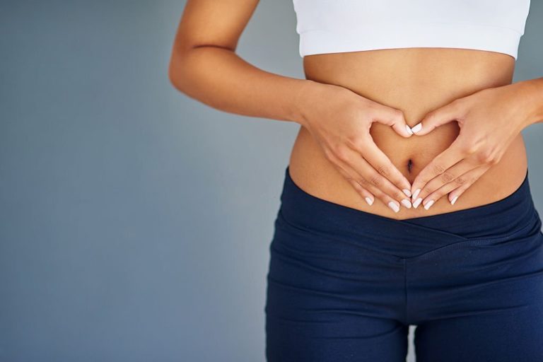 Fit young woman making a heart-shaped gesture over her stomach in Salt Lake City, UT | Santosh Yoga Institute