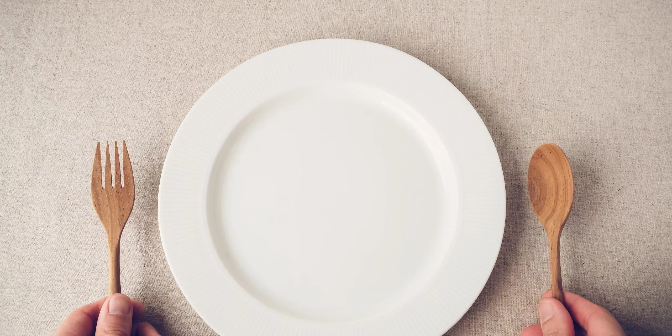 White plate on table man hands holding fork and spoon in Salt Lake City, UT | Santosh Yoga Institute