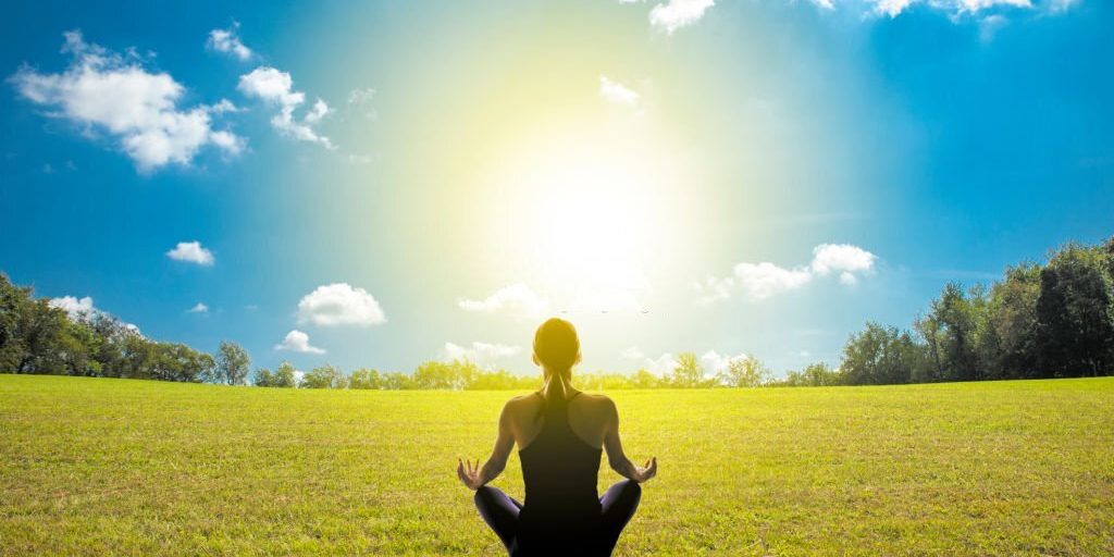 Young female sitting in beautiful garden doing meditation yoga in Salt Lake City, UT | Santosh Yoga Institute