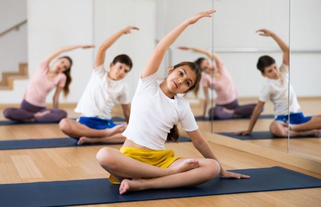 Children are sitting on a mat and doing yoga in Salt Lake City, UT | Santosh Yoga Institute